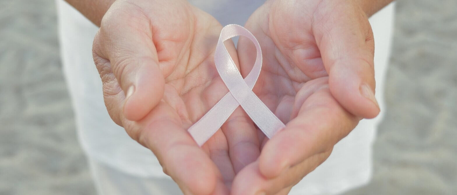 Hands holding pink cancer ribbon
