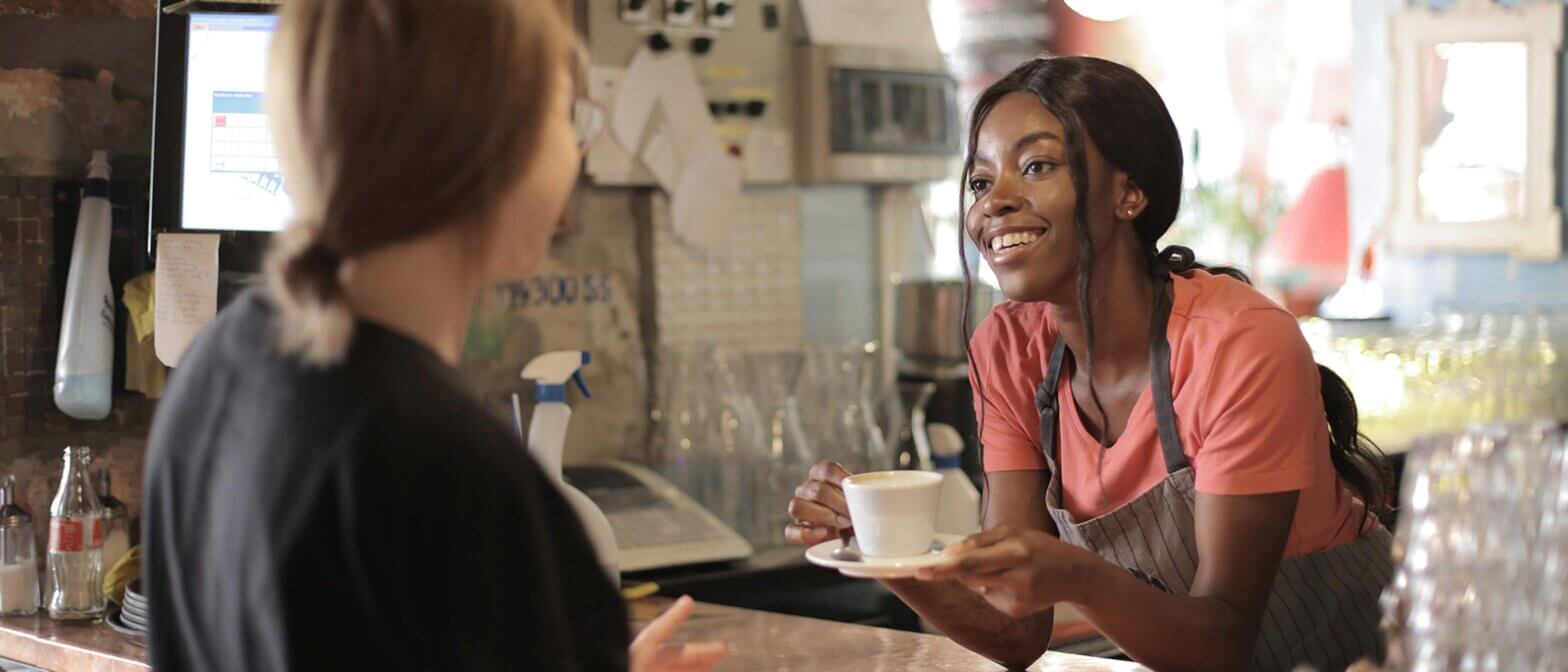 A coffee shop employees talks to a customer