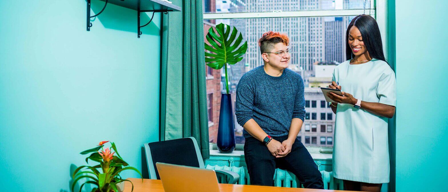 Employee taking notes while talking with other employee
