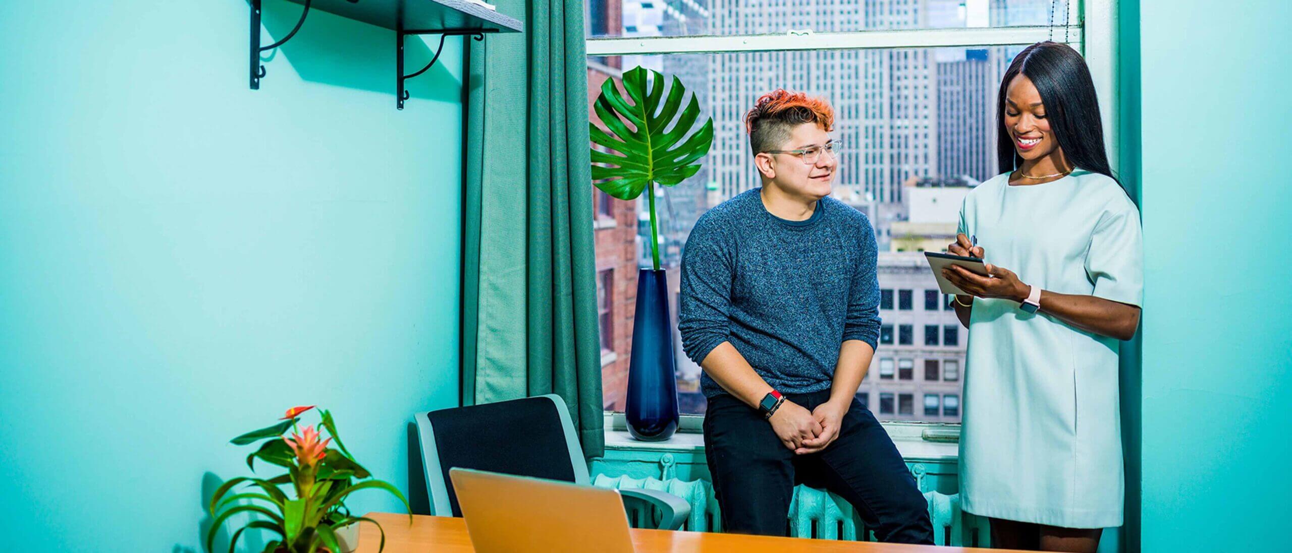 Employee taking notes while talking with other employee