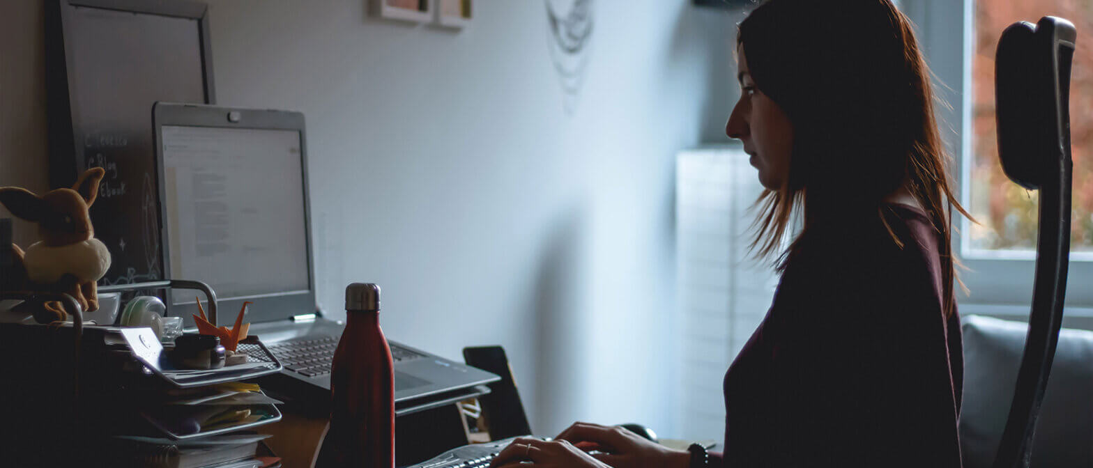 Employee working at laptop in dark room