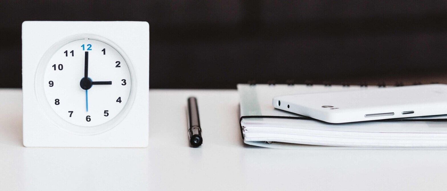 Clock with pen and files on desk