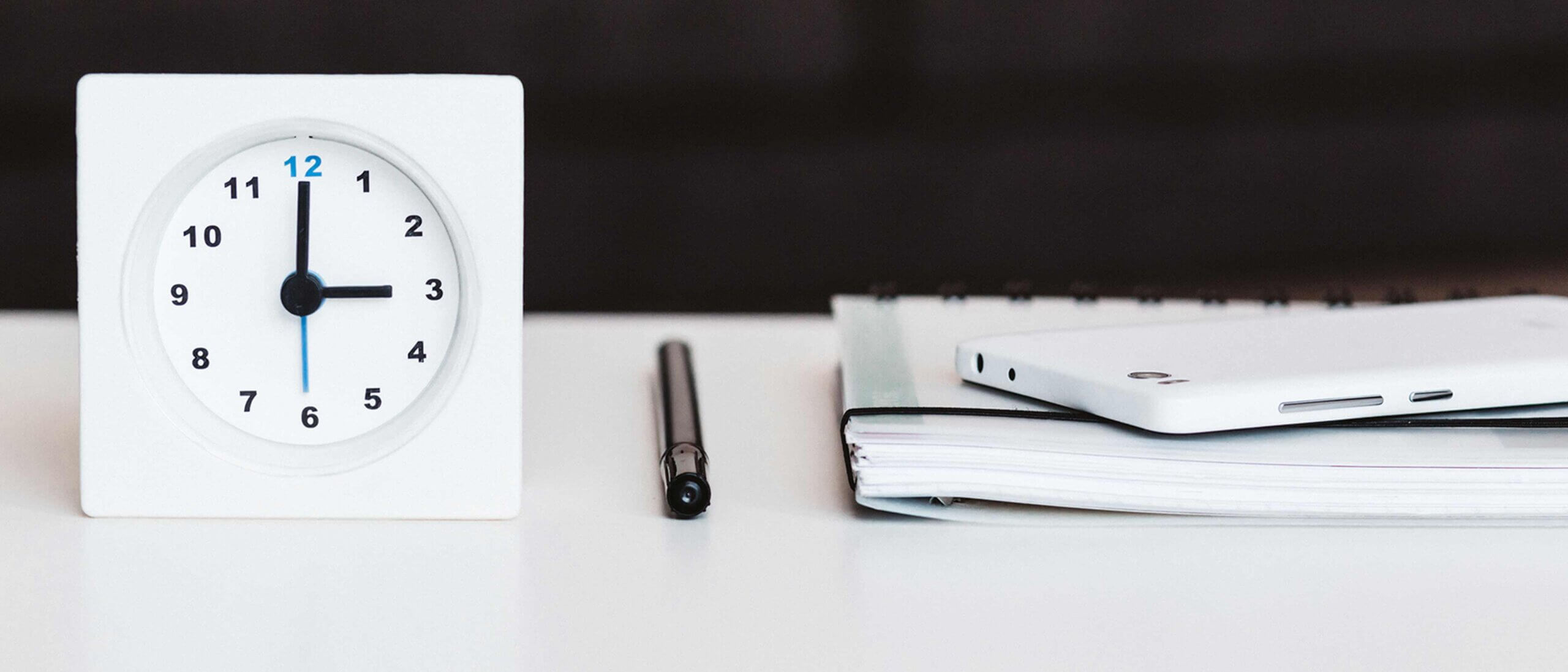 Clock with pen and files on desk