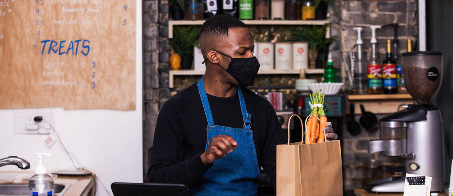 Grocery clerk wearing a mask while bagging fresh produce
